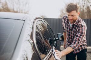 young man wiping his car after car wash