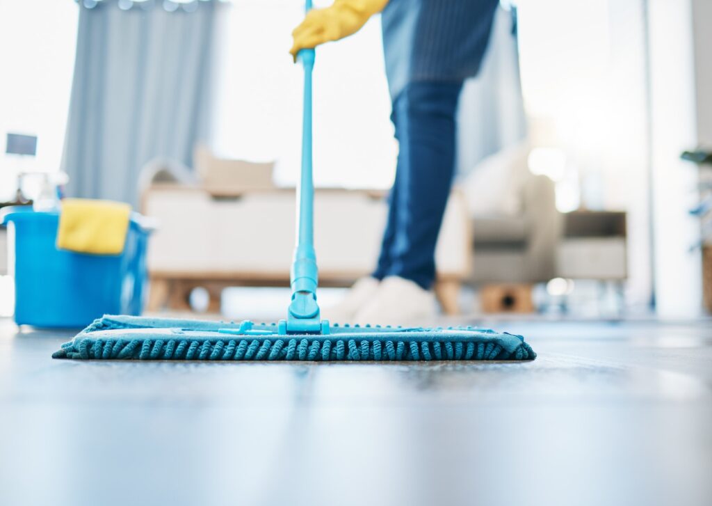 Housekeeping, cleaning and woman maid with a mop to clean the living room floor at a house. Female