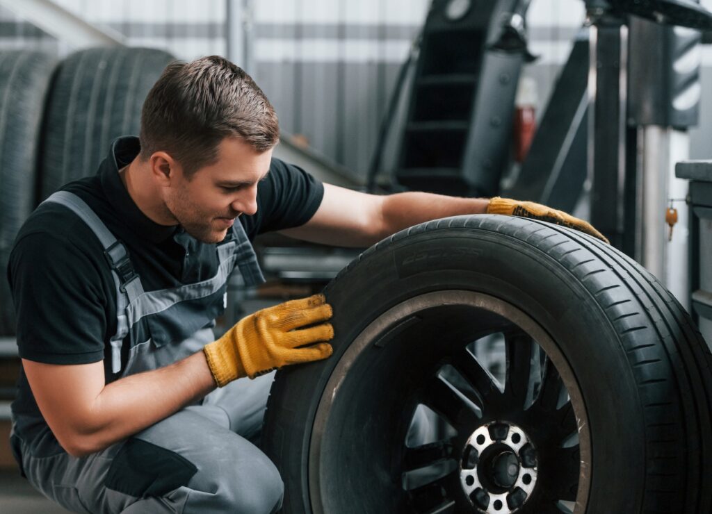 Replacement of the old tire. Man in uniform is working in the auto service
